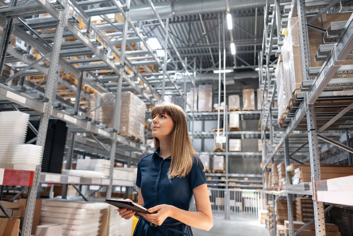 A woman with an iPad in a supply chain hub, seeing data science impact on business.